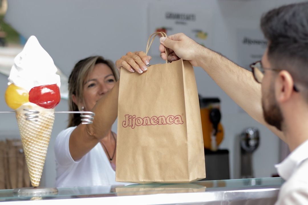 Una clienta recibe su compra de Jijonenca en el mostrador de una heladería